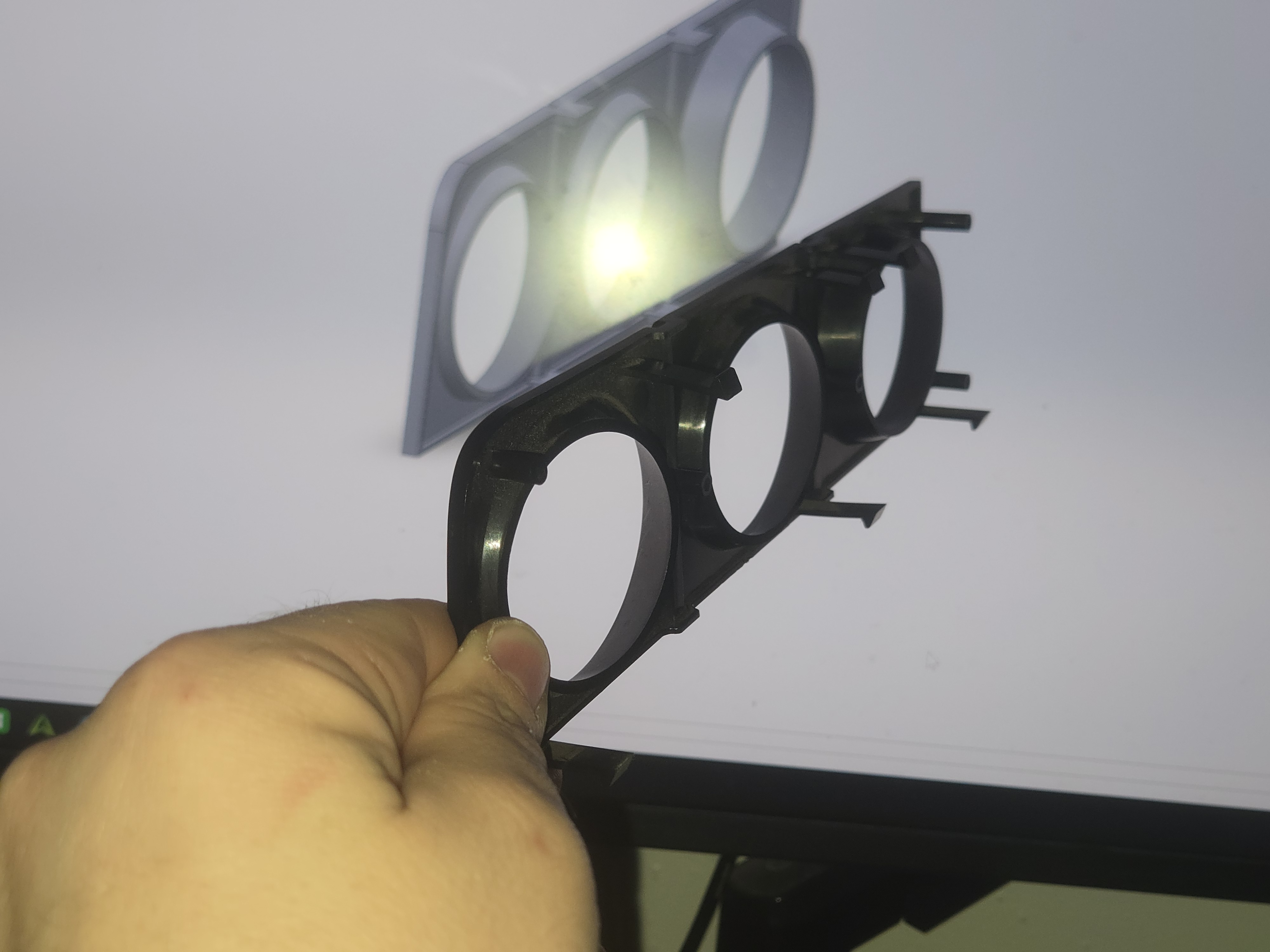 Original OEM bezel held up against the SolidWorks model on screen.
